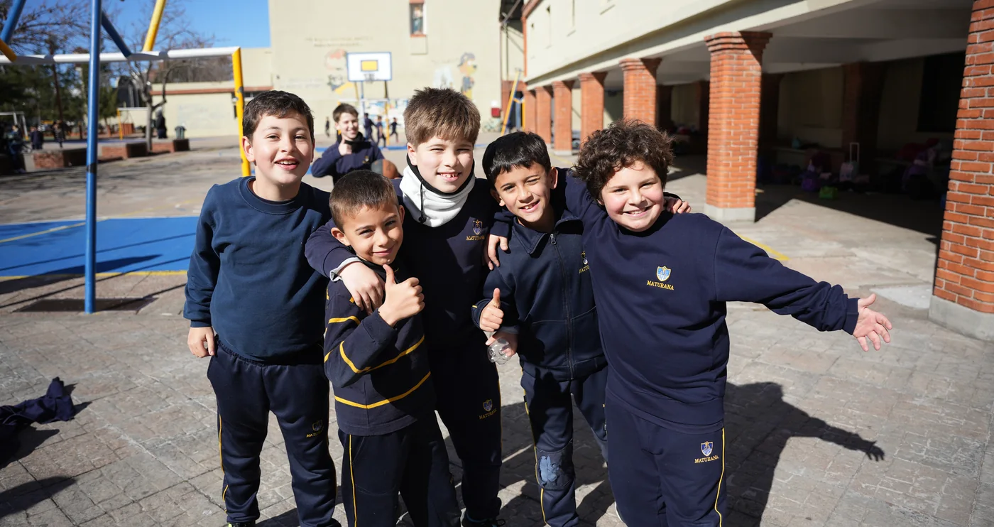 Cinco estudiantes de Primaria se abrazan y sonríen juntos en el patio de Maturana.
