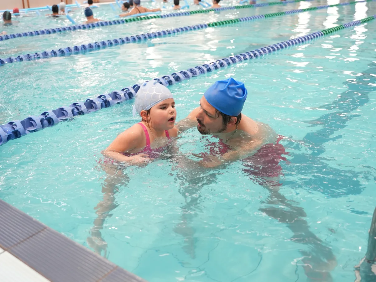 Una niña de Inicial practica natación acompañada por un docente.