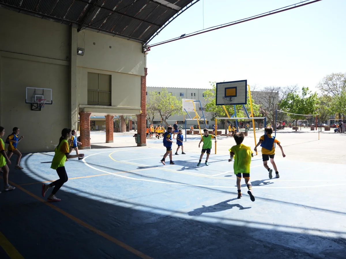 Estudiantes de Primaria participan en un juego deportivo en la cancha cubierta.