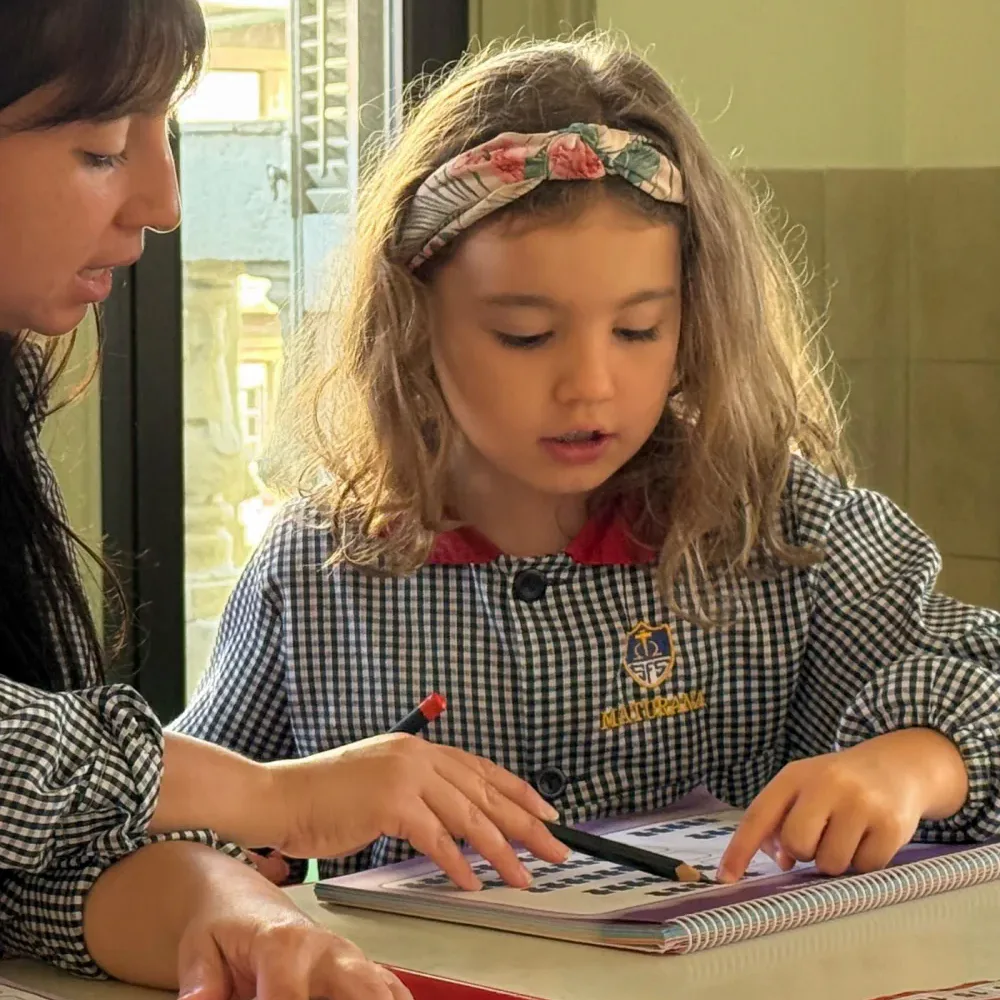 Niña de inicial jugando con bloques junto a una educadora.