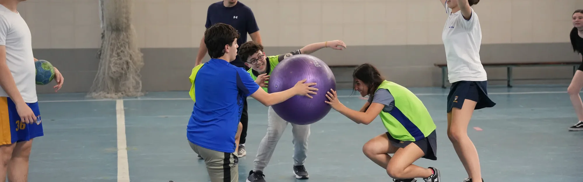 Estudiantes de Ciclo Básico participando en una actividad deportiva en el gimnasio.