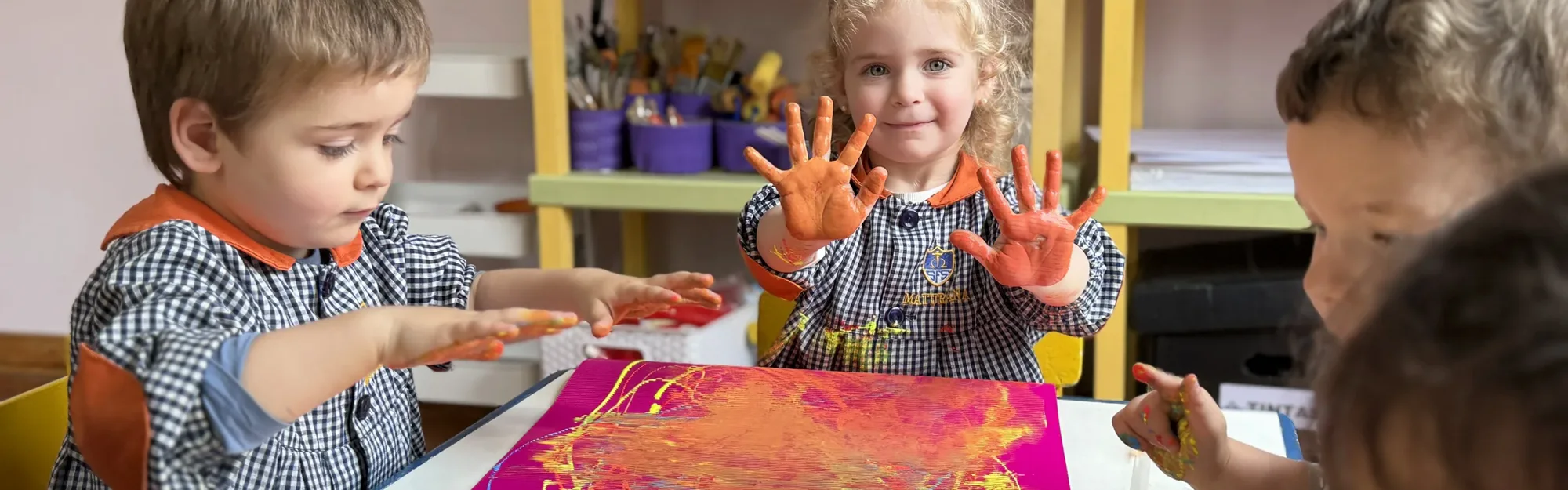 Niños de Maternal pintando con las manos en una actividad de exploración artística.
